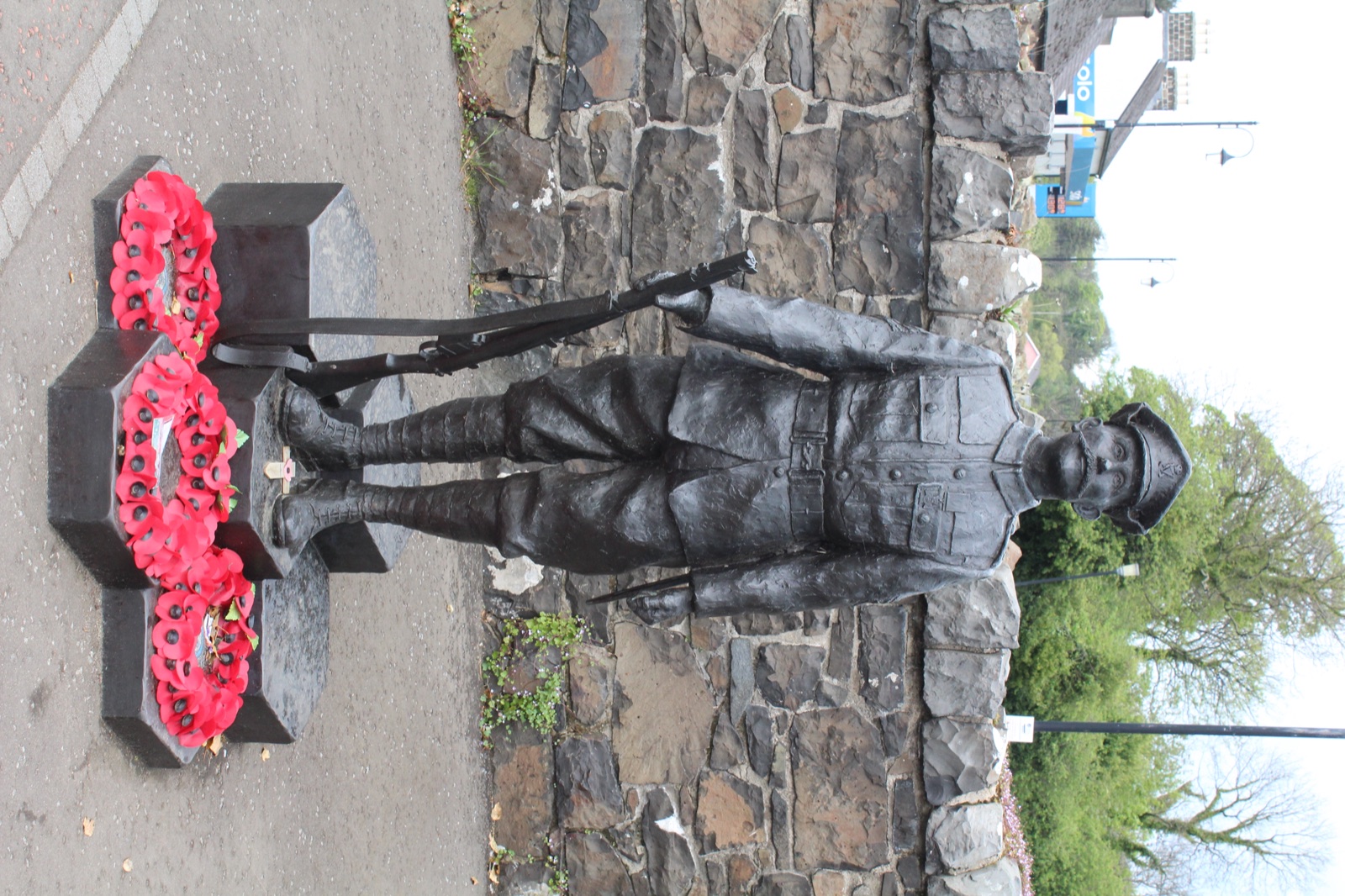 A bronze statue of Sergeant Robert Quigg VC in Bushmills, standing with his rifle and poppy wreaths at the base