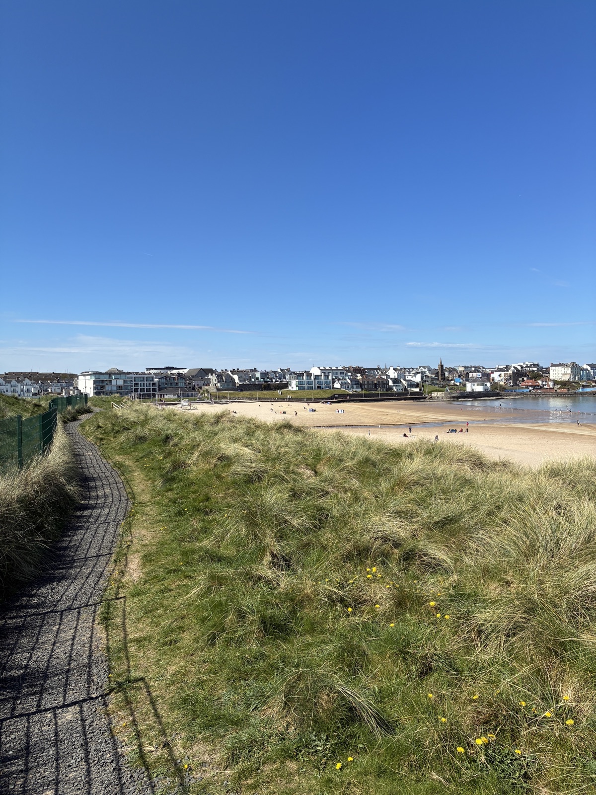 The dune path above East Strand beach in Portrush, with the town and beach visible beyond