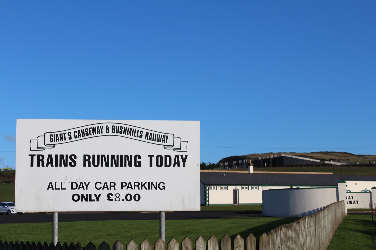 A roadside sign reading Giant's Causeway and Bushmills Railway, Trains Running Today, All Day Car Parking Only £8.00
