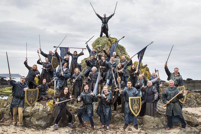 A group of Game of Thrones-costumed tour guests posing on the Causeway stones with swords and shields