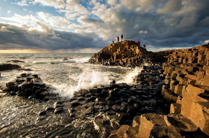Giant’s Causeway basalt columns at sunset, with waves breaking over the rocks